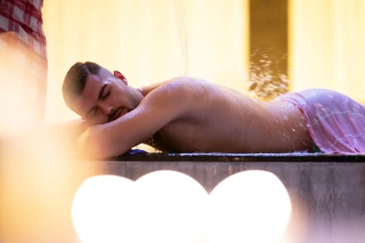 Water Treatment in Turkish Hammam.Man receiving water therapy inside a traditional Turkish hammam with ornate details.