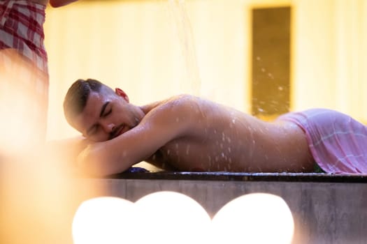 Water Treatment in Turkish Hammam.Man receiving water therapy inside a traditional Turkish hammam with ornate details.