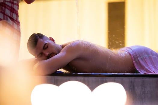 Water Treatment in Turkish Hammam.Man receiving water therapy inside a traditional Turkish hammam with ornate details.
