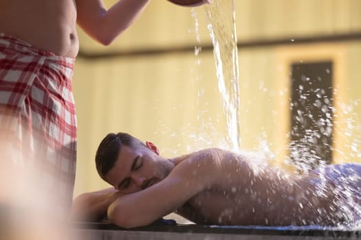 Water Treatment in Turkish Hammam.Man receiving water therapy inside a traditional Turkish hammam with ornate details.