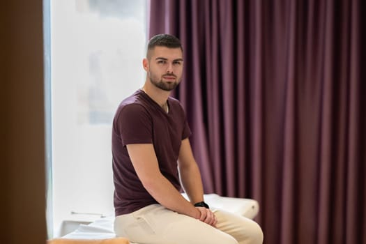 Man Waiting for Therapy Session. A man sitting calmly on a treatment table, waiting for a physical therapy session in a clinic environment.