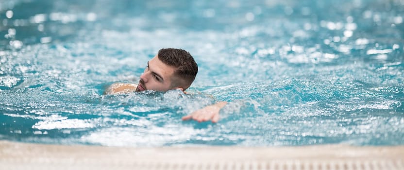 Swimming for Therapy. A man doing aquatic therapy or swimming exercises in a professional spa facility indoor pool.