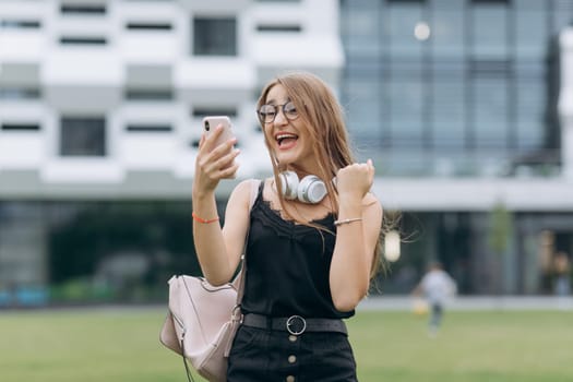Young woman is having good news at the smartphone. Young couple enjoying a good news received over phone. Laughing girl having a nice conversation on mobile phone.