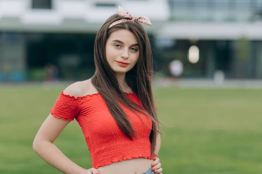 Cheerful casual young woman looking at camera. Woman with long sexy healthy hair in khaki top and ripped jeans