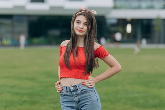 Caucasian female university student looking at camera smiling happy. Beautiful brunette woman with long sexy healthy hair in khaki top and ripped jeans