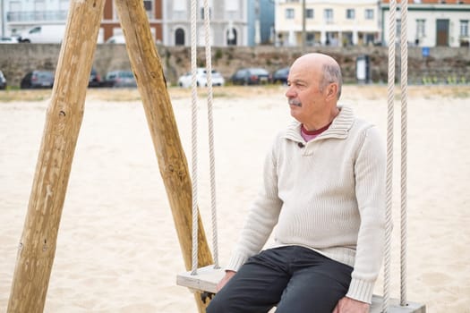 Elderly Man Sitting on a Swing at the Beach Reflecting on Life. High quality photo