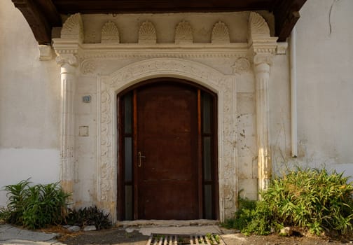 Old arched stone doorway in a house with white walls in Cyprus, reflecting traditional Mediterranean architecture.