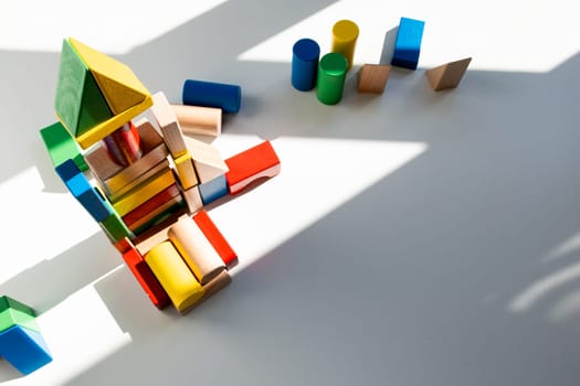 Colorful wooden building blocks in sunlight on white background. High quality.