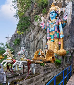 Kuala Lumpur, Malaysia - February 18, 2025: Large statue of Hindu deity Vishnu with chariot and horses at the base of the cliffs, at Batu Caves temple complex