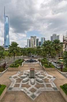 Kuala Lumpur, Malaysia - March 1, 2025: View of Kuala Lumpur city featuring the distinctive Merdeka 118 tower among modern skyscrapers. Lush palm trees frame the vibrant cityscape on a cloudy day