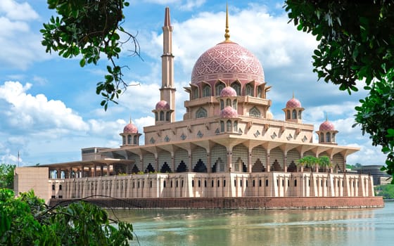 The Putra Mosque stands majestically by the tranquil lake in Putrajaya, Malaysia. Its pink dome and intricate designs captivate visitors, embodying the cultural heritage of the region