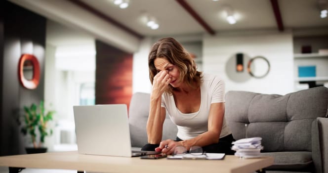 Stressed Accountant Woman Confronts Tax Bill Paperwork On Laptop Sofa.