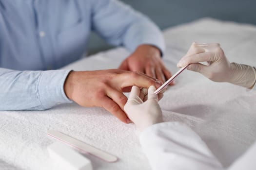 Therapist Man Carefully Shaping Cuticles And Applying Nail Polish.