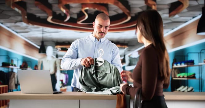 Happy Customer Pays Cashier For Fashionable Clothes At Retail Store.