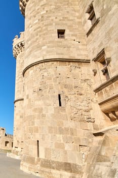 Close-up of an ancient castle's textured stone walls and circular tower, highlighting the historical architecture under bright daylight.