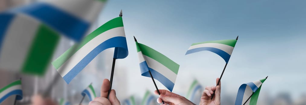 Sierra Leone flags in their hands on a blurred urban background. The photo illustration was created without the use of artificial intelligence, only using Photoshop.