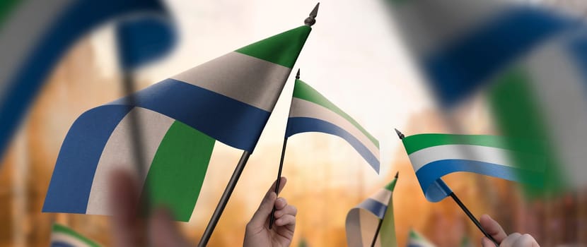 Sierra Leone flags in their hands on a blurred urban background. The photo illustration was created without the use of artificial intelligence, only using Photoshop.