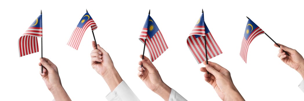 The Malaysia flag in hand in different angles on a white background.