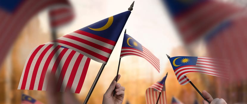 Malaysia flags in their hands on a blurred urban background. The photo illustration was created without the use of artificial intelligence, only using Photoshop.