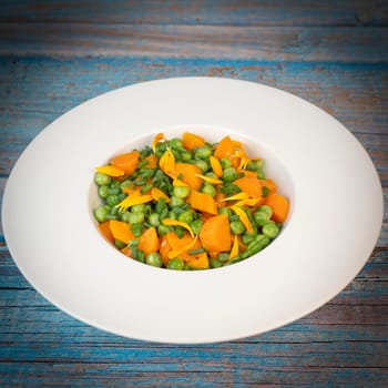 Fresh garden peas and carrots are cooked with salted butter, then garnished with chives and bright marigold flowers for an appealing and colorful side dish.