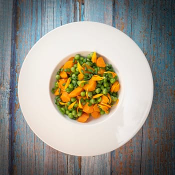 Fresh garden peas and carrots are cooked with salted butter, then garnished with chives and bright marigold flowers for an appealing and colorful side dish.