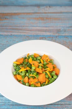 Fresh garden peas and carrots are cooked with salted butter, then garnished with chives and bright marigold flowers for an appealing and colorful side dish.