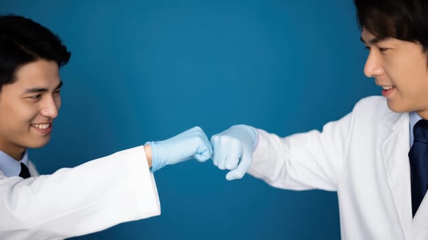 This mid-shot captures two individuals, possibly medical professionals, in white lab coats and blue medical gloves, engaging in a celebratory fist bump against a vibrant blue background, highlighting their collaboration. AI generated.