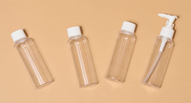 Travel set of plastic bottles for cosmetics on beige background, top view