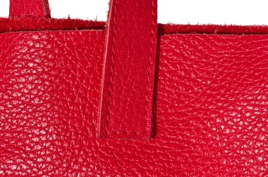 A fragment of the handle of a red leather bag, showing the grainy texture of the material and the quality of the stitching