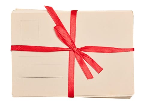 A stack of blank postcards tied with a red ribbon and bow, isolated background.