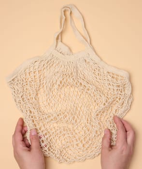 Empty reusable cotton mesh bag in female hands