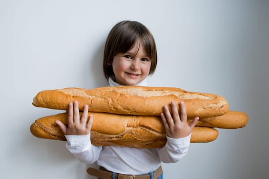 Caucasian female child smiling holding baguettes against white background.