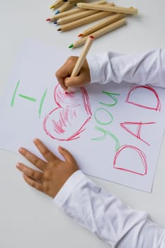 Child drawing father day card with colorful pencils.