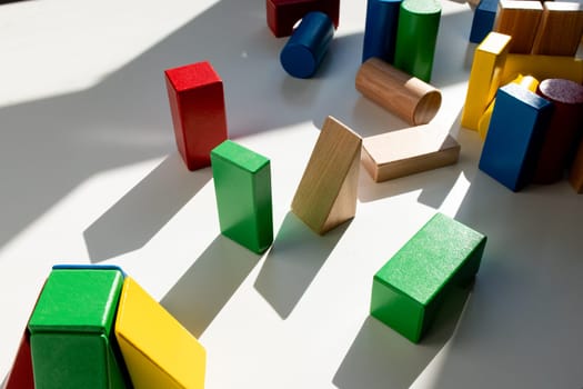 Colorful wooden blocks in sunlight on white surface. High quality.