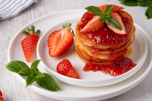 Mini pancakes with strawberry jam and strawberries.