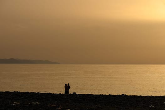 Father holds his young child on the beach in Cyprus