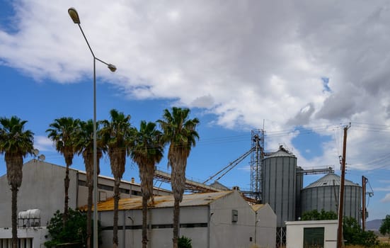 Large grain elevator facility located in the Cypriot countryside, used for storing and processing harvested cereals like wheat and barley.