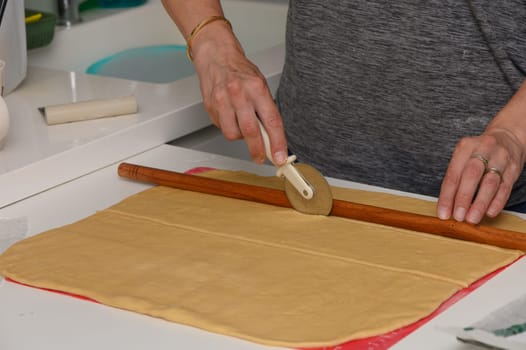 Woman Cutting Dough into Portions with Pizza Cutter for Baking Preparation