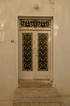 Weathered white wooden door with rustic texture on a traditional home in Cyprus, evoking Mediterranean charm.