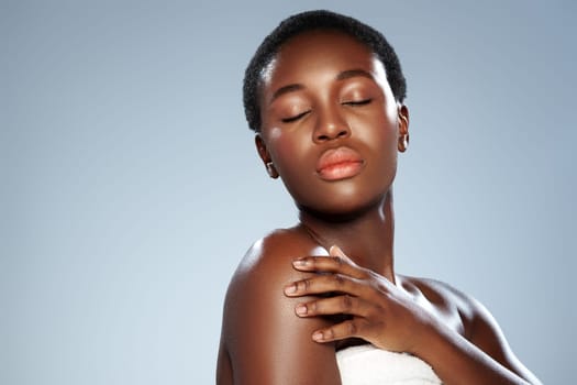A woman with short hair poses gracefully in a studio, her eyes closed and expression serene. Soft lighting highlights her features, emphasizing natural beauty and elegance.