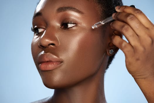A woman focuses on applying a serum to her cheek in a well-lit area, highlighting her glowing skin. The serene background complements her beauty routine.