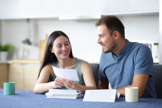 Happy interracial couple talking about letter in the kitchen at home