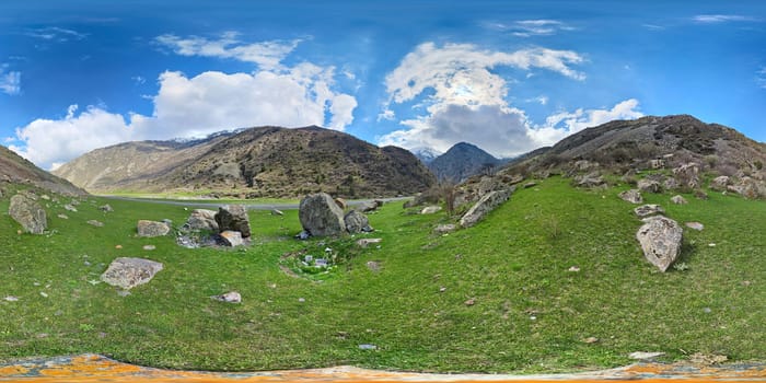 A 360 by 180 degrees equirectangular Spherical Panorama of Mountain Valley green pasture with scattered rocks at springtime day