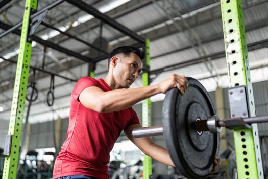 A man lifts a barbell in the gym, demonstrating focus and dedication to strength training.