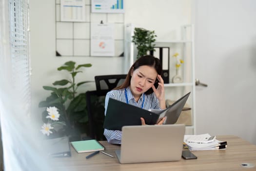 A young woman appears deep in thought while reviewing documents, reflecting a moment of concentration in a modern workspace.