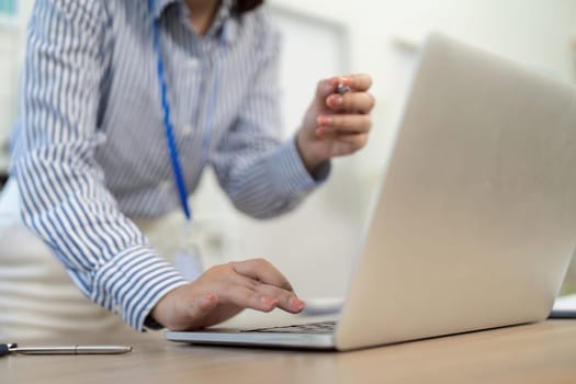 A determined professional woman engages with her laptop, preparing for a meeting in a sleek office environment.