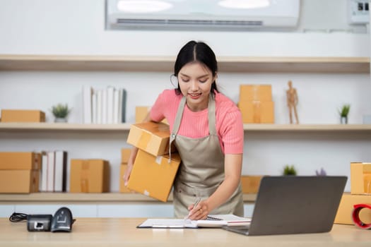 A dedicated entrepreneur writes down orders while packing boxes, illustrating the essence of small business operations.