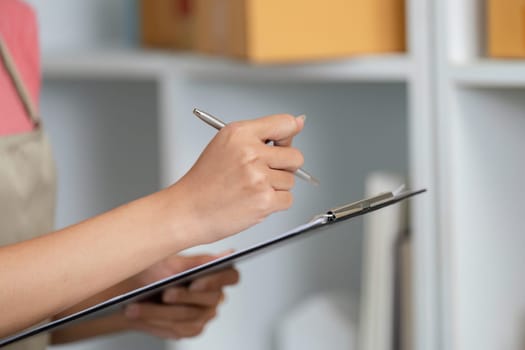 An entrepreneur jotting down notes in a microbusiness setting, emphasizing organization and management skills.