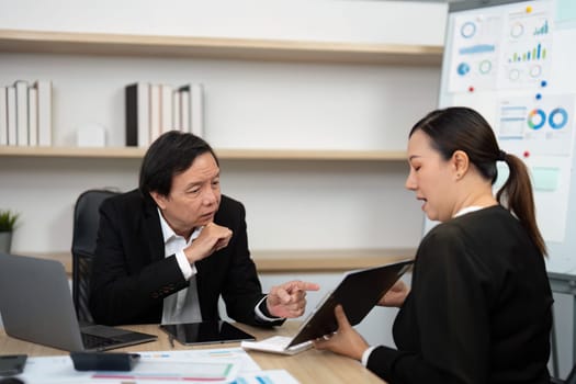 A business consultant shares insights from a tablet with a male client during a strategy meeting.