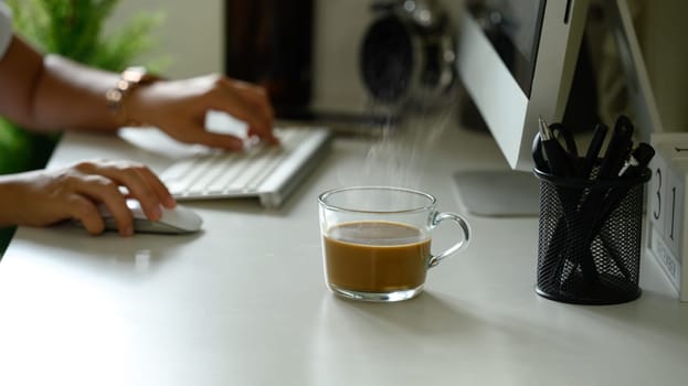 Focus and fresh brew glass mug of hot coffee placed on a working desk.